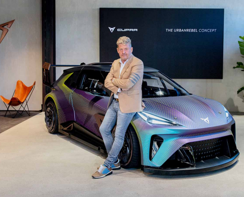 CEO of CUPRA car brand leaning on the hood of an electric CUPRA in iridescent purple.