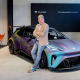 CEO of CUPRA car brand leaning on the hood of an electric CUPRA in iridescent purple.